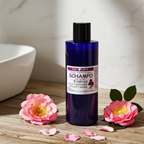 Plastflaska med MacUrth Vildros shampoo på träyta, omgiven av vildrosblommor och lösa kronblad, varmt och inbjudande ljus.